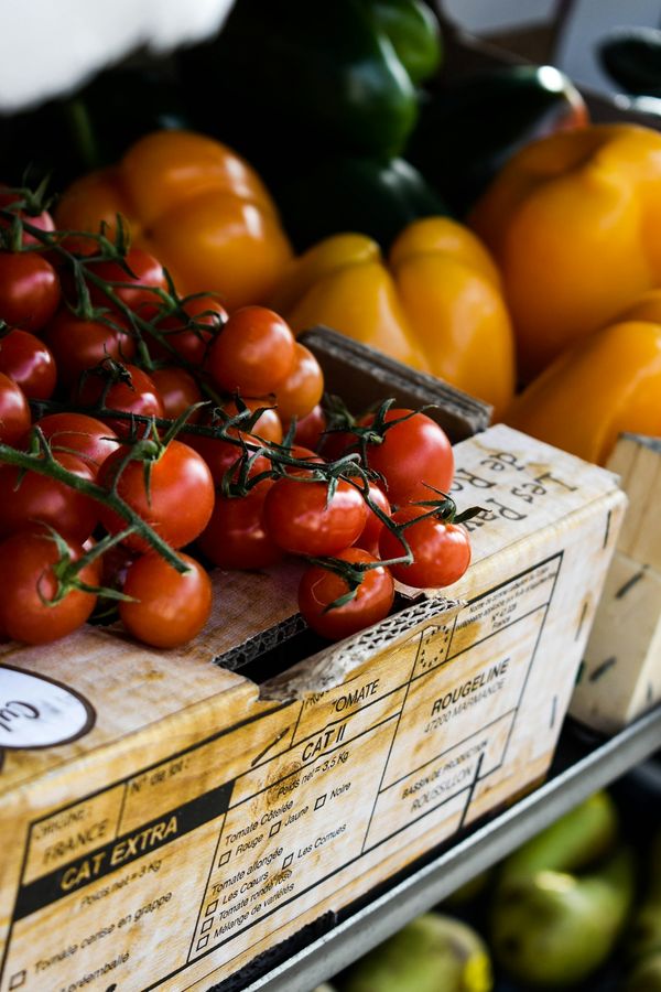 Jitomates en rama y pimientos en una caja